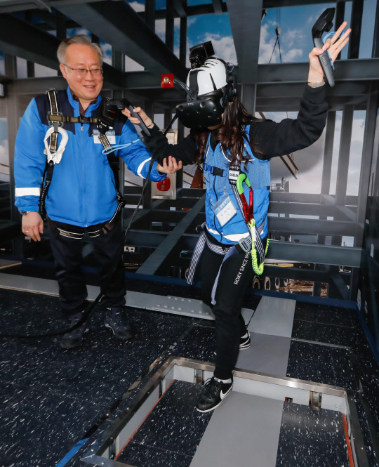 대림그룹 신입사원이 VR장비를 착용하고 강사의 안내를 받으며 고소 작업을 체험하고 있다. <대림산업 제공>